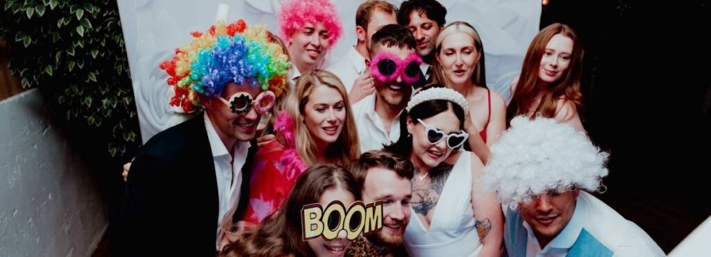 bride and groom taking photo booth picture with friends at wedding