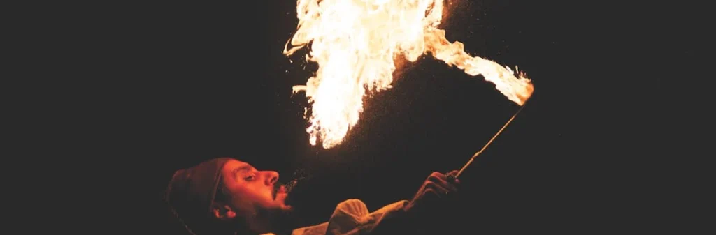 person in a dark space blowing fire into the air as a wedding circus act