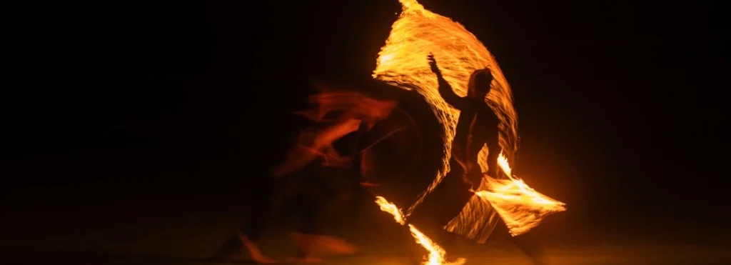 two fire dancers in a dark space fire dancing at a wedding