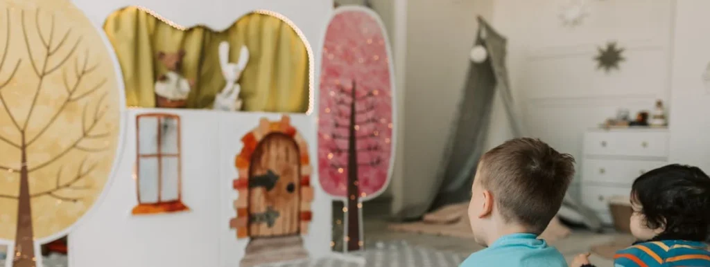 two children seated on the floor facing a a puppet show at a wedding
