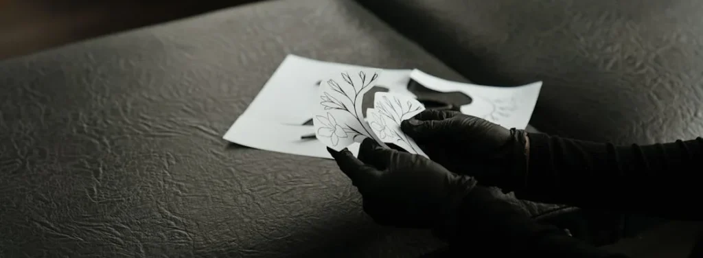 a black table with tattoo artist holding a stencil for wedding flash tattoo bar
