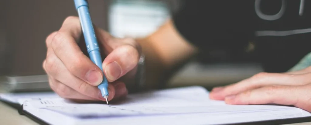 a person writing in a notebook for wedding trivia