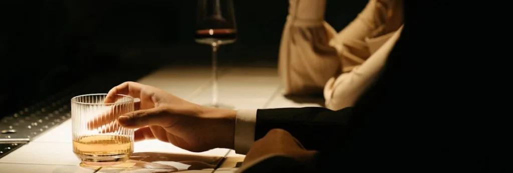 mand and woman sitting at a counter with a glass of whisky and glass of wine for wedding whisky tasting