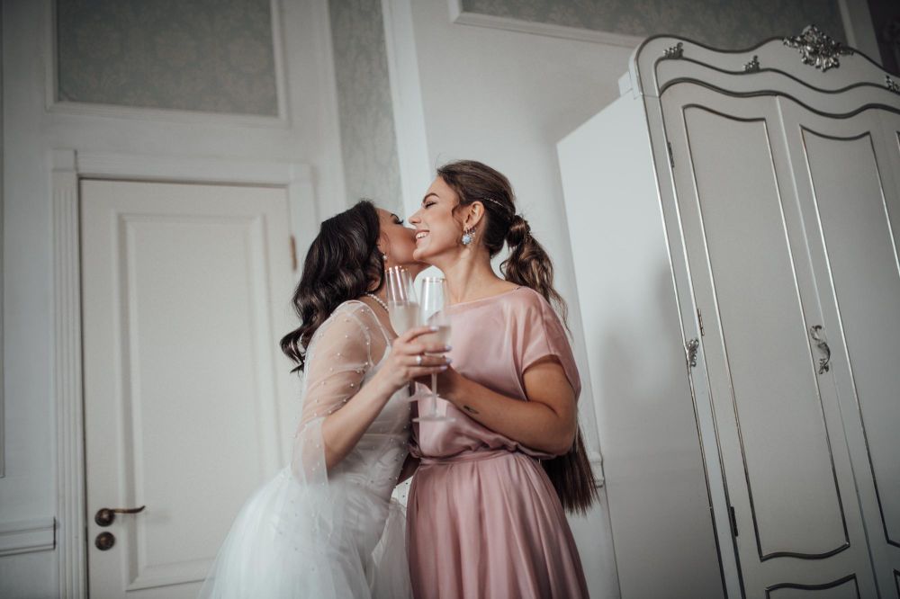 married lesbian couple embracing each other at their wedding with a champagne glass in hand