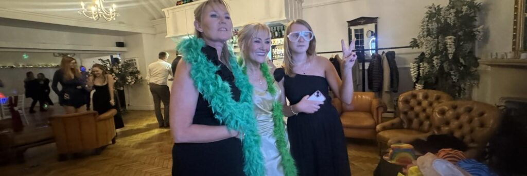 three wedding guests with photo booth props at a wedding