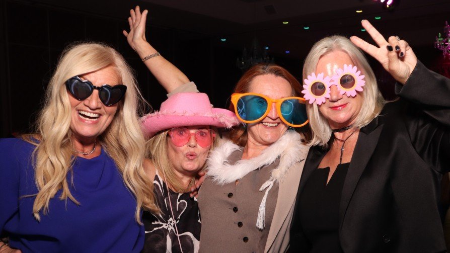 4 women taking a picture on a photo booth at a wedding