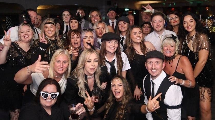 people in gatsy themed clothes at a birthday party taking a picture